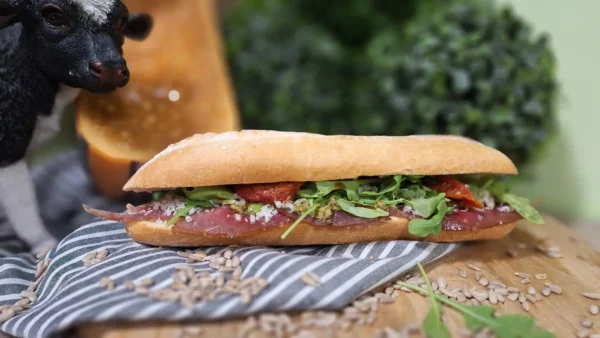 Broodje Carpaccio: vers belegd broodje met carpaccio, rucola, zongedroogde tomaatjes, zonnebloempitjes, groene pesto, balsamico-dressing en parmezaan.