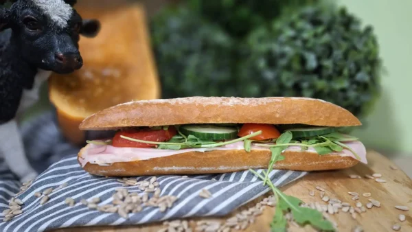 Broodje Ham de Luxe: vers belegd broodje met gekookte ham, roomkaas met bieslook, rucola, tomaat en komkommer.
